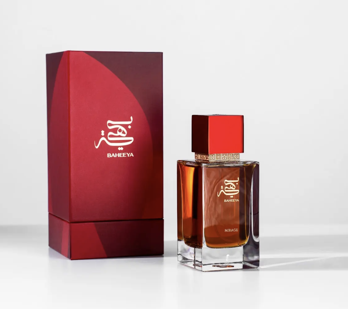 A bottle of Baheeya perfume with amber liquid and a red cap stands next to its matching red box on a clean white background.