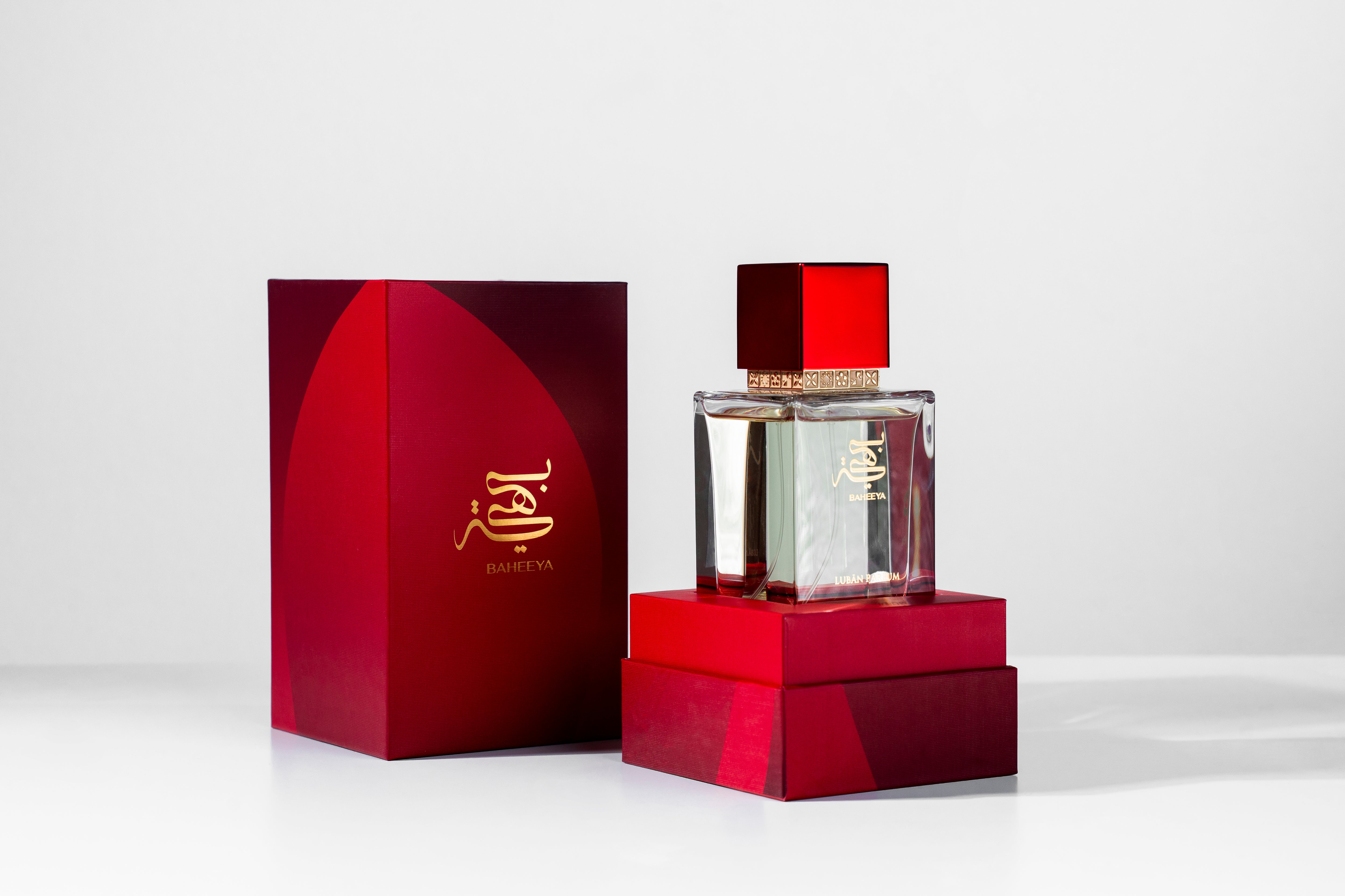 Perfume bottle and packaging with red and gold design on a white background